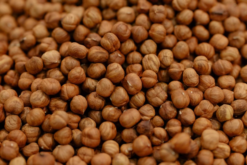 A detailed close-up of raw hazelnuts, showcasing their rich brown texture and natural patterns.